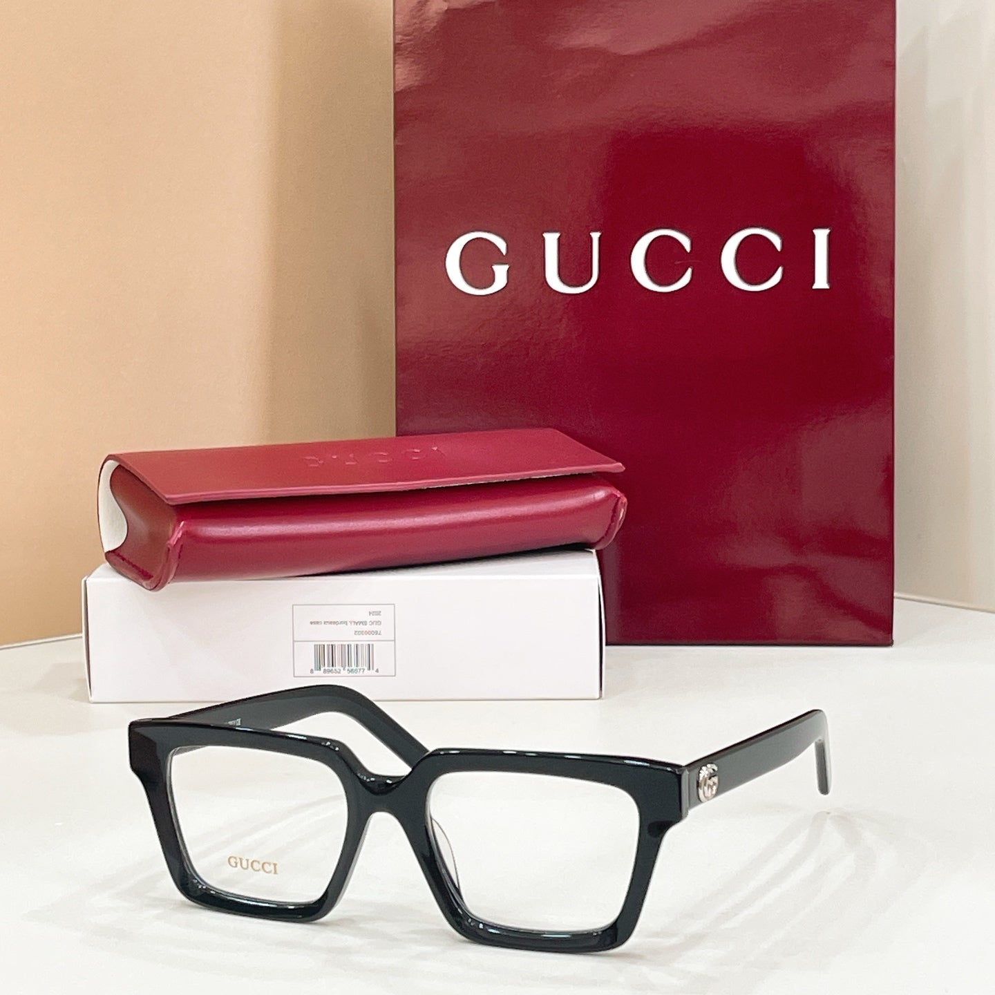 Rectangular eyeglasses with dark frame and light lenses, gold-tone temple logo detail