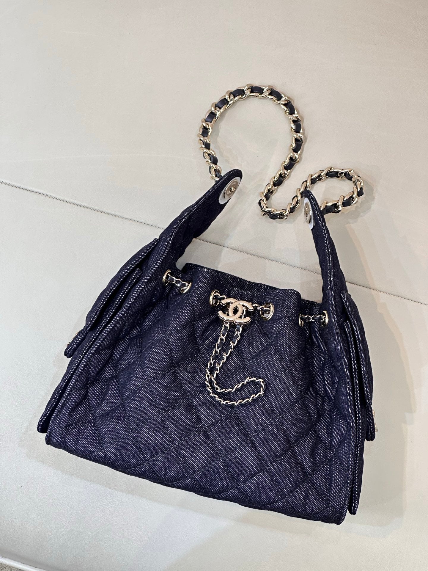 Chanel quilted dark blue bucket bag with chain strap and gold logo hardware