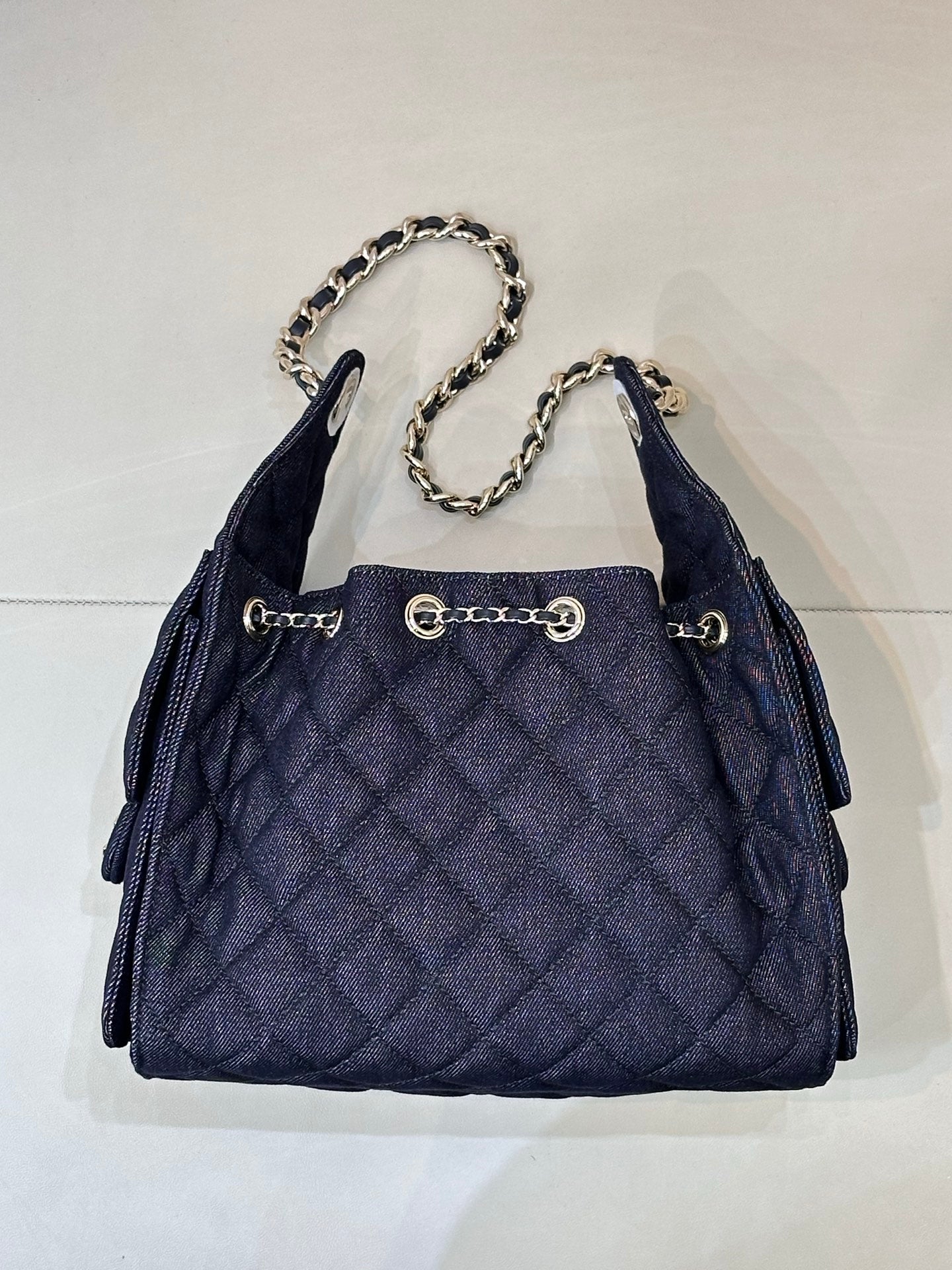 Chanel quilted dark blue bucket bag with chain top handle and gold ring charm