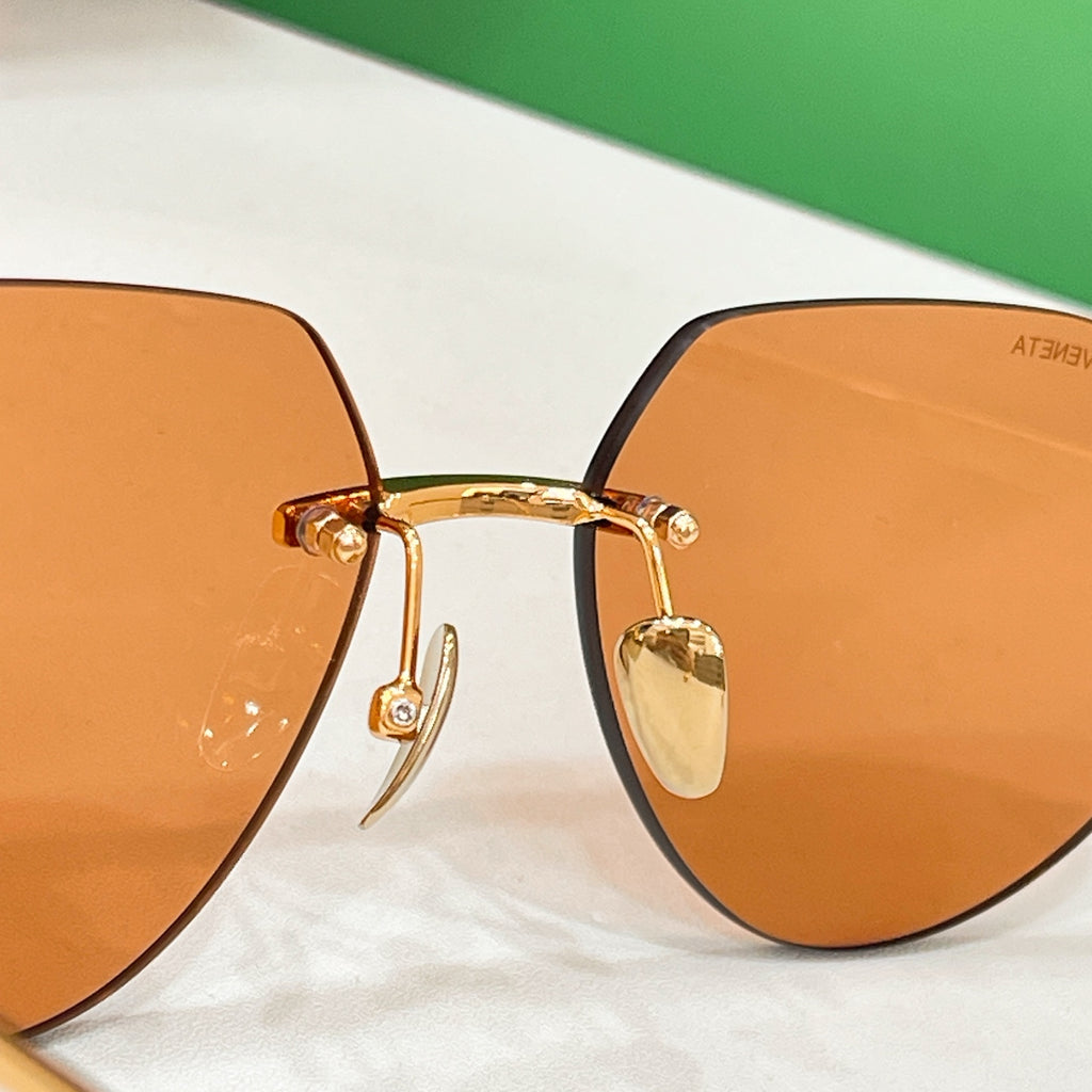Bottega Veneta aviator sunglasses close-up with amber lenses and gold bridge
