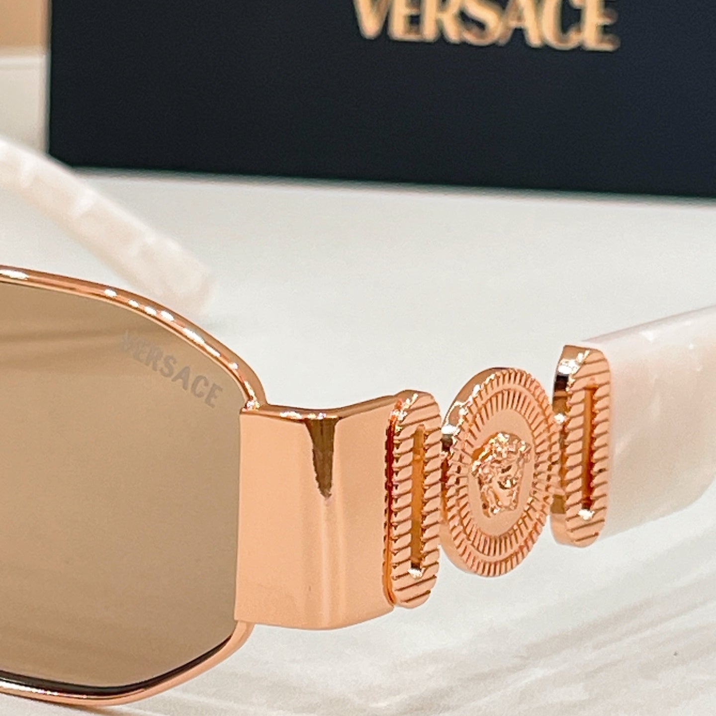 Sunglasses temple hinge with gold-tone logo medallion detail