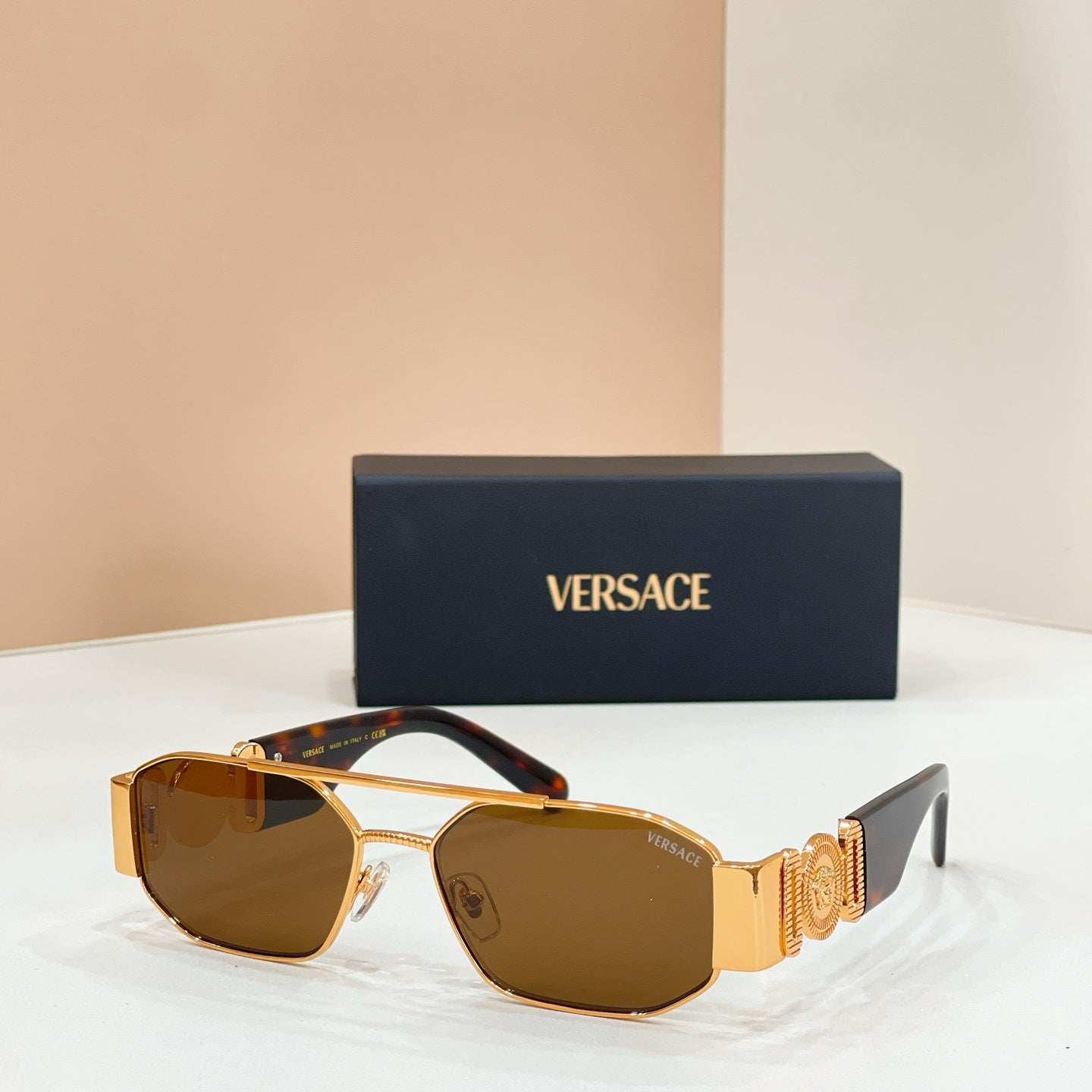 Versace sunglasses with brown lenses, gold frame, and patterned logo temple arms