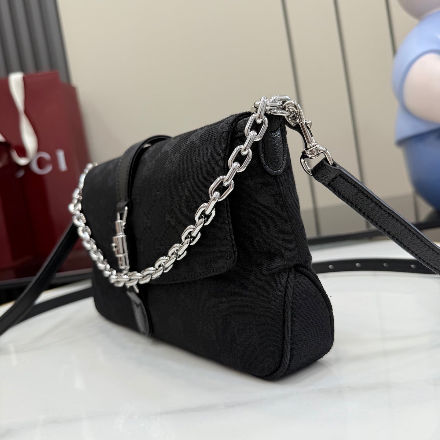 Gucci mini chain shoulder bag in black fabric with front flap, clasp, and adjustable strap