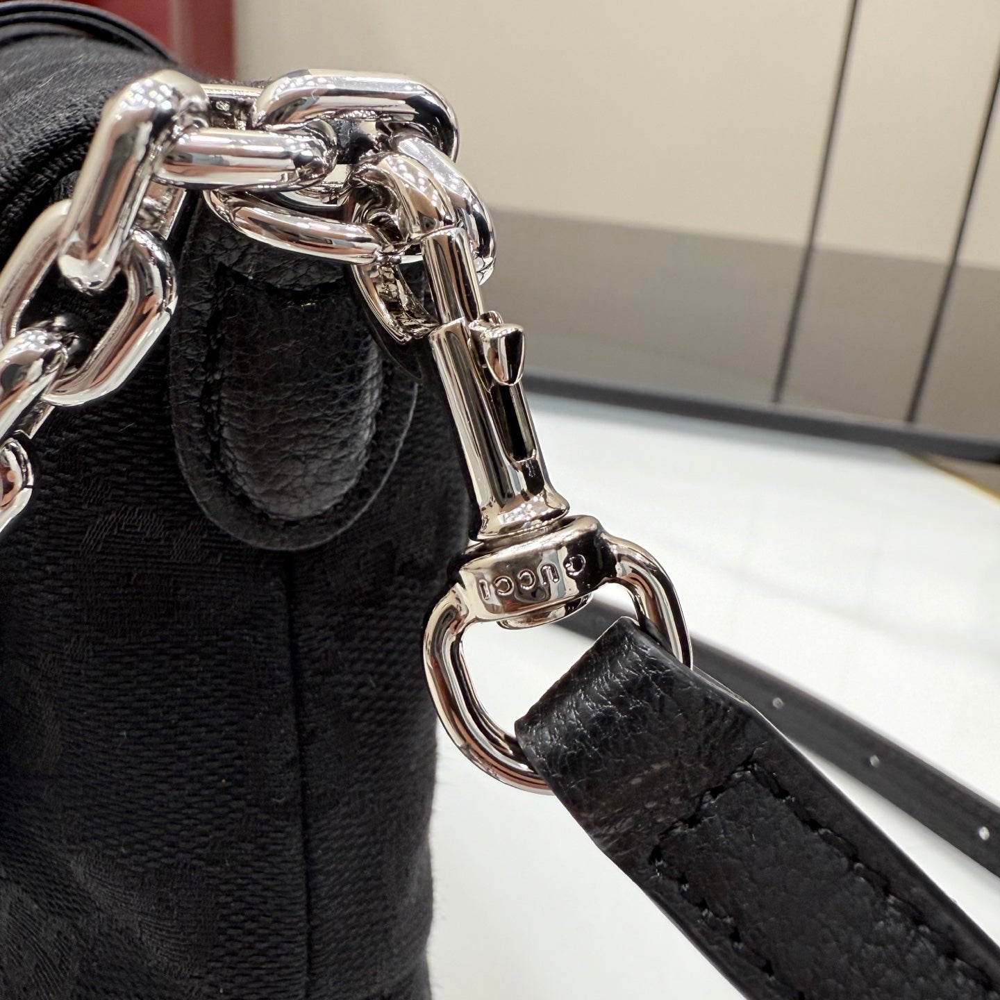Gucci bag with black leather strap and silver-tone chain hardware clasp detail