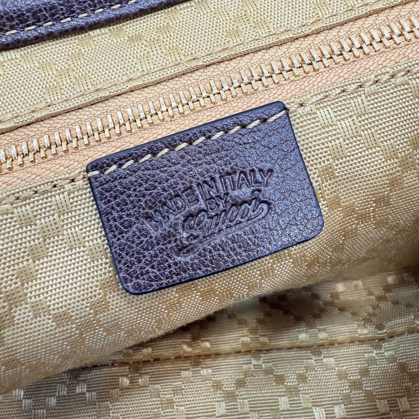 Embossed leather label inside the beige GG canvas bag with dark blue backing