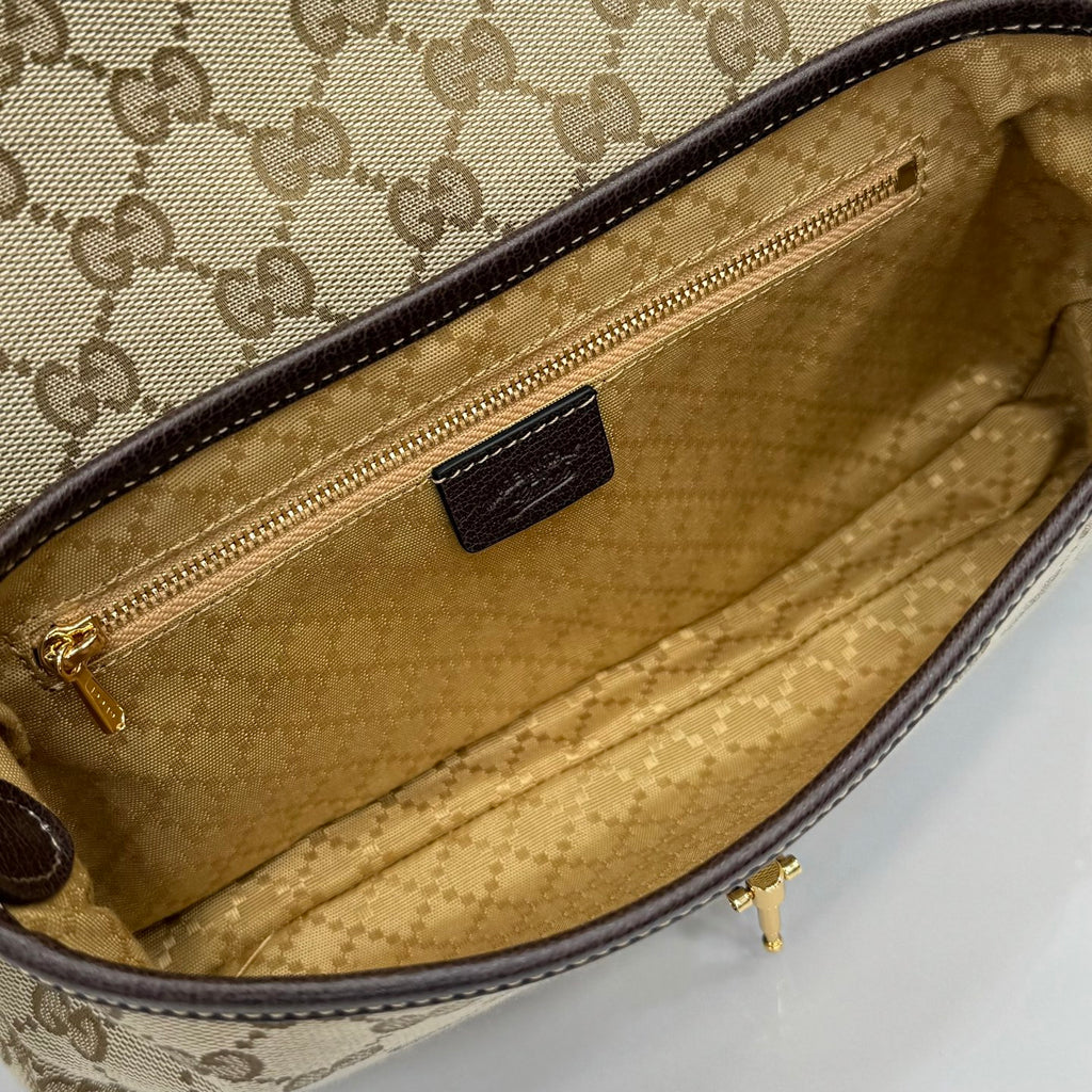 Open interior of beige GG canvas bag with brown lining, zip pocket, and leather slot