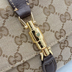 Gold-tone clasp with green accent on brown leather and beige GG canvas shoulder bag