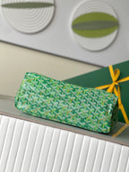 Green patterned clutch-style handbag with zipper top and gold ribbon detail