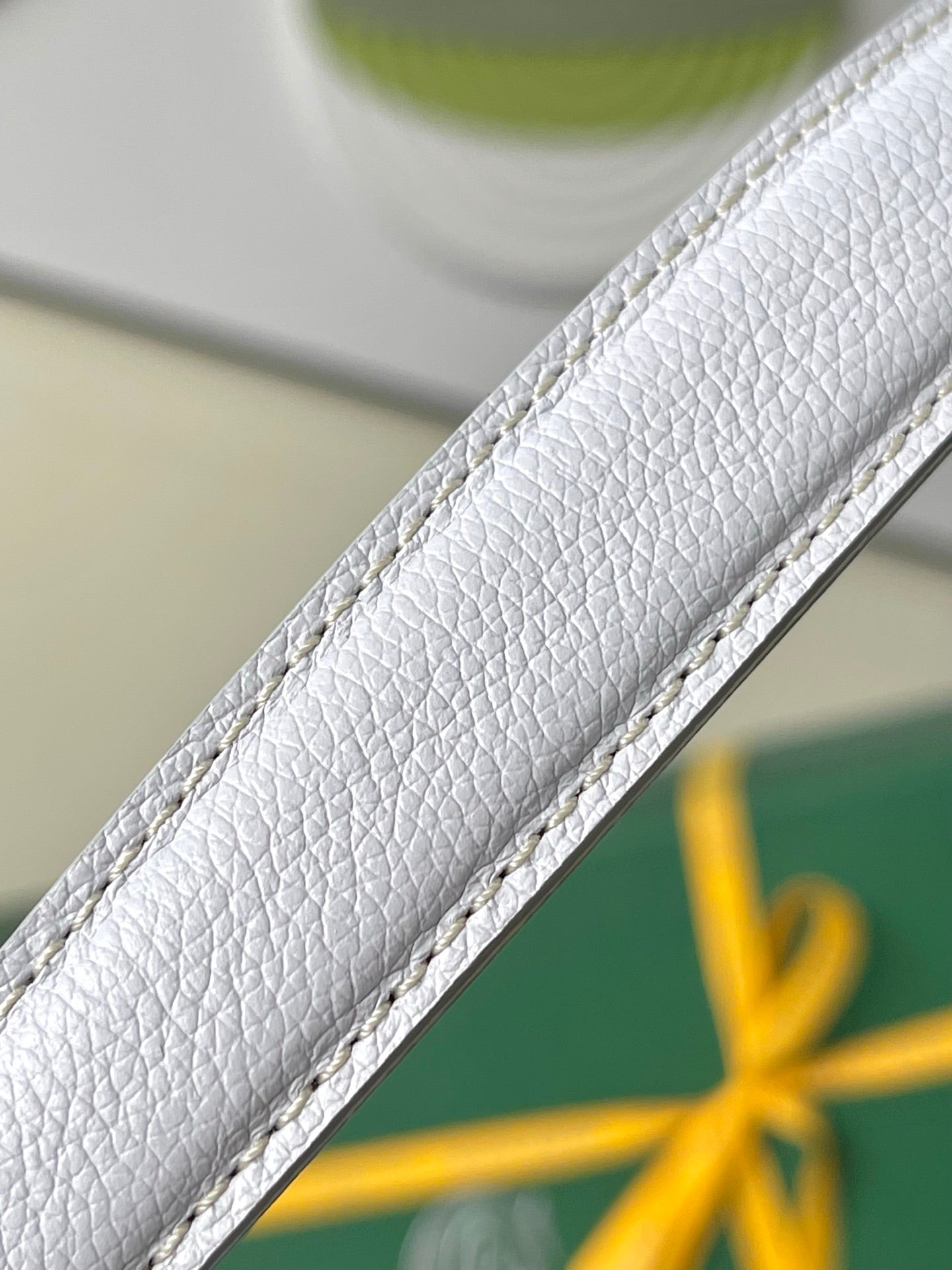 Light blue-and-white bag strap edge with pebbled leather texture and stitched trim.