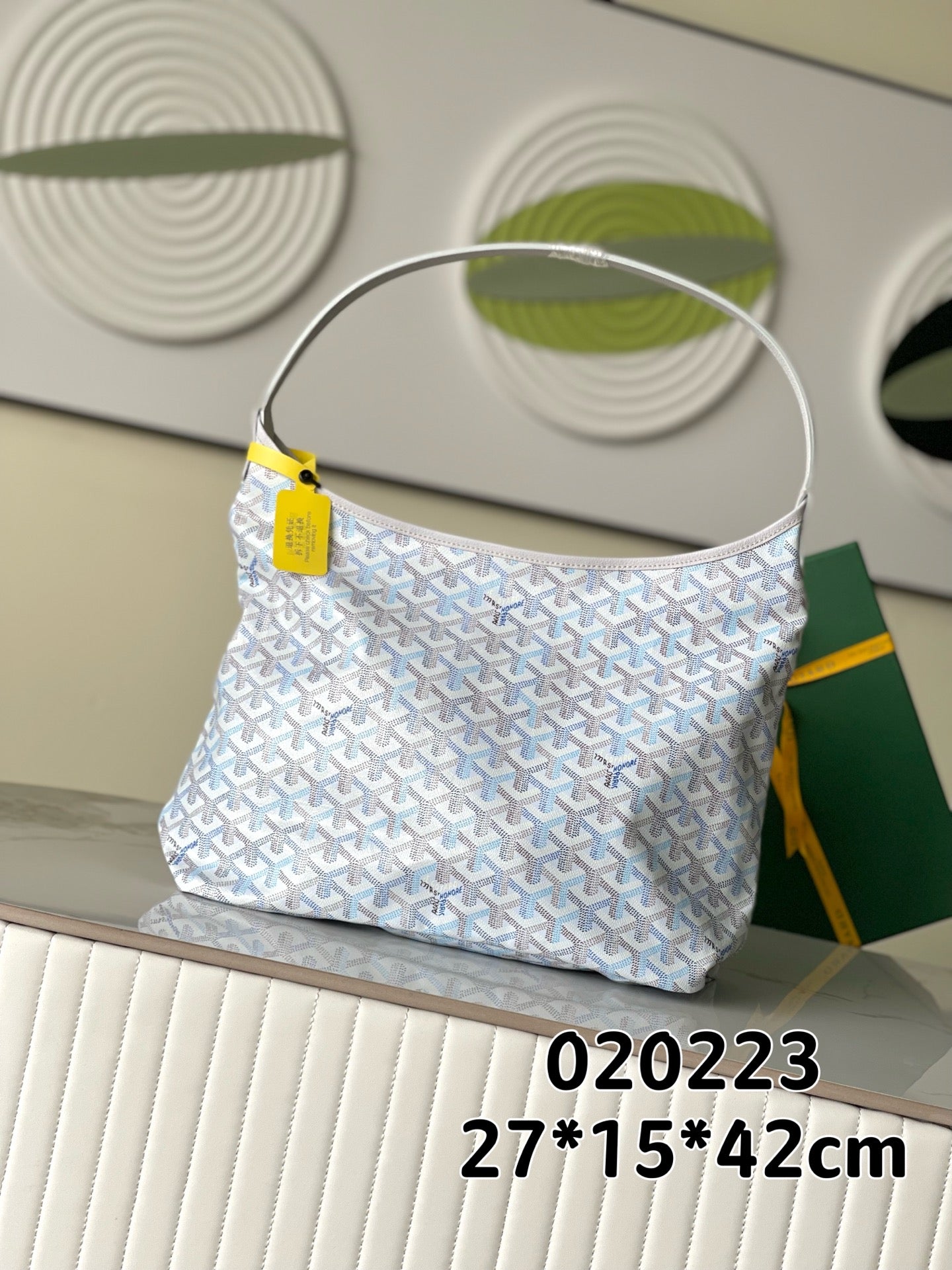 Goyard-pattern hobo bag in light blue and white, top handle and yellow tag detail.