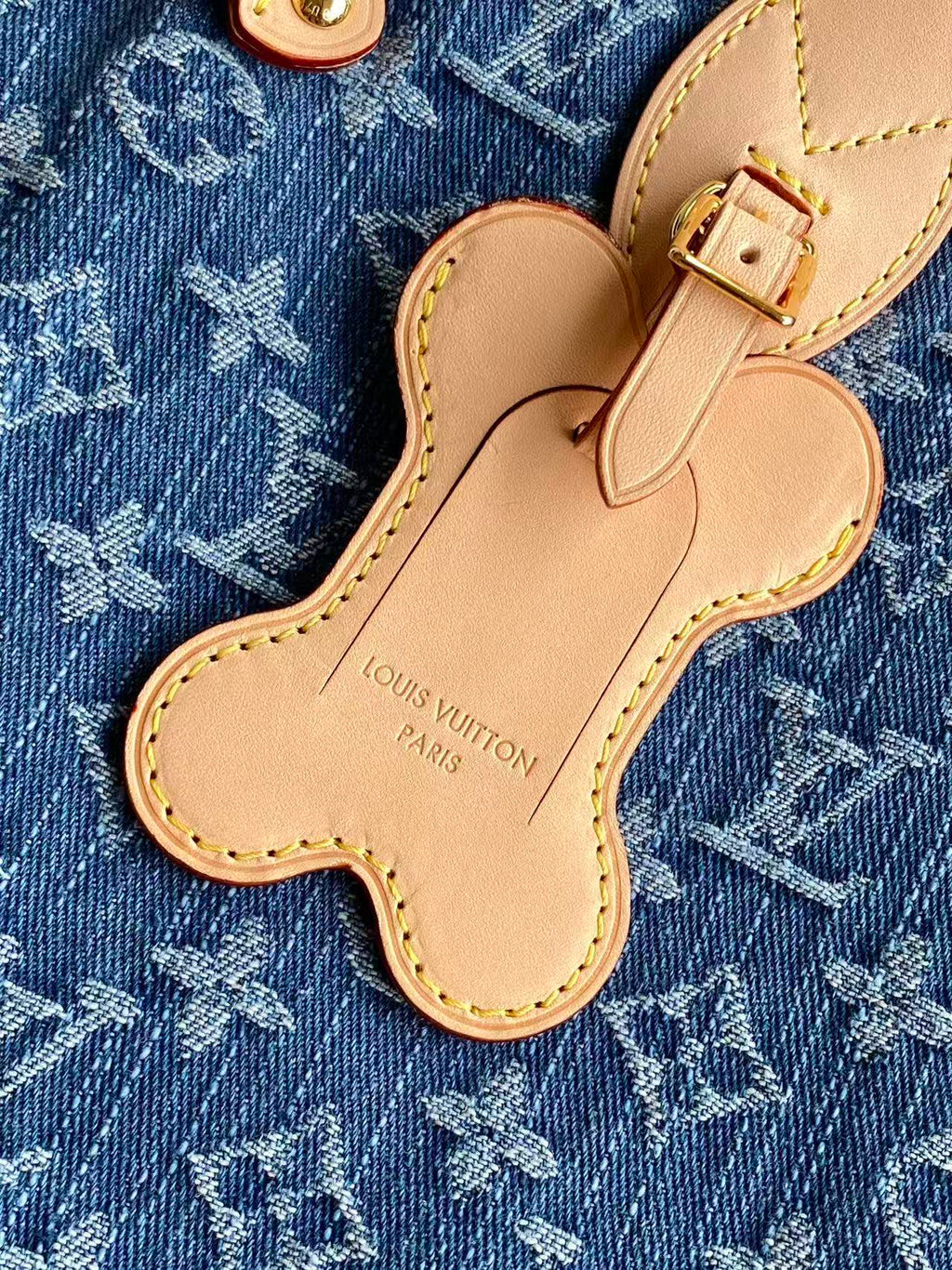 Louis Vuitton monogram bag charm shaped like a clover on blue fabric