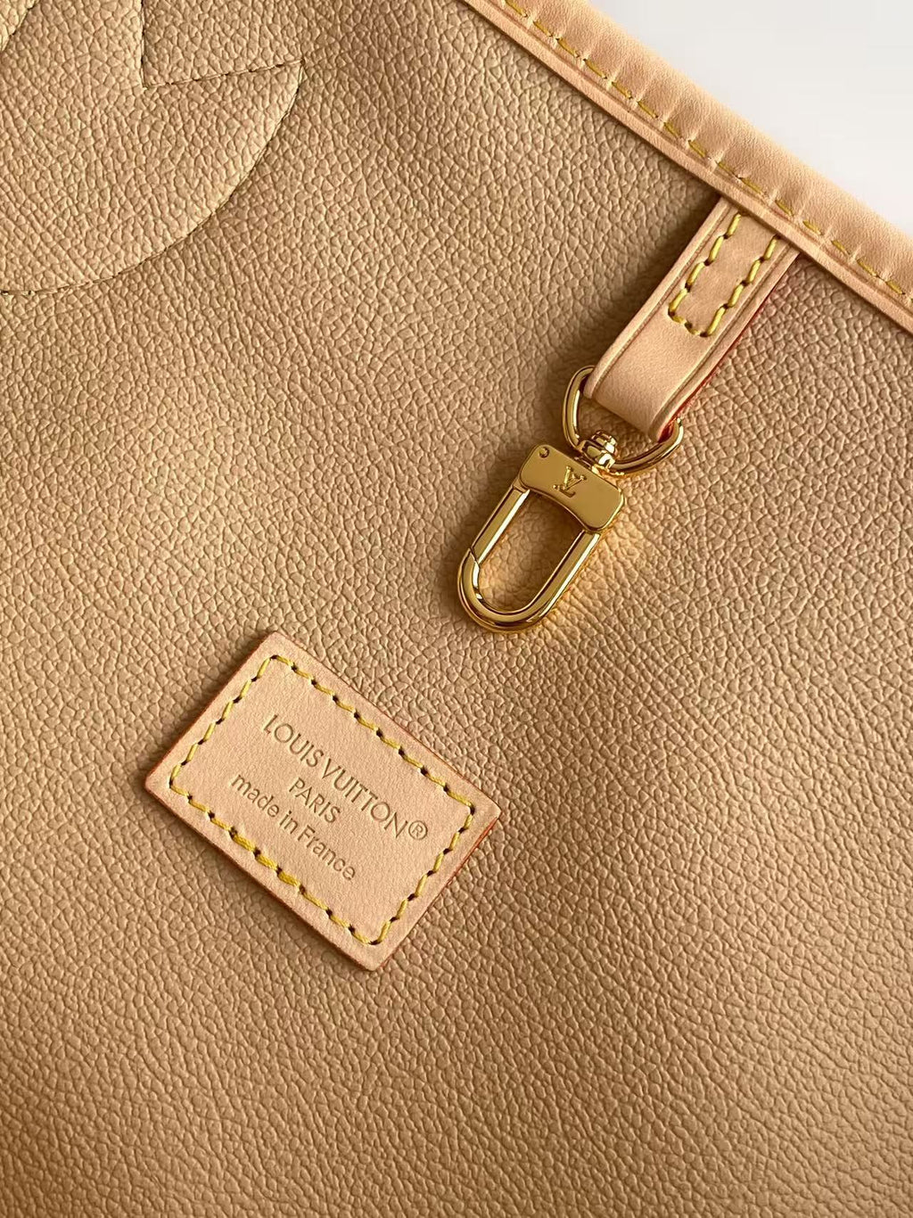 Louis Vuitton leather label and gold-tone clasp on tan bag interior