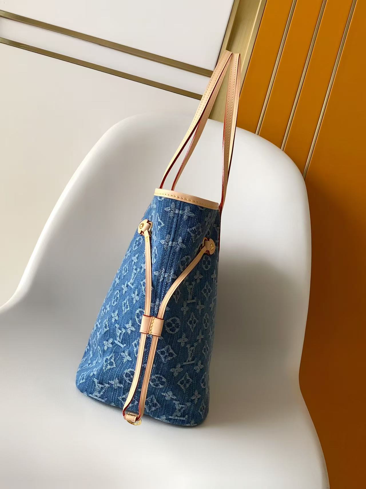 Louis Vuitton monogram tote bag shown from the side, blue with tan handles