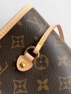 Louis Vuitton monogram tote bag close-up of tan strap loop and gold hardware ring