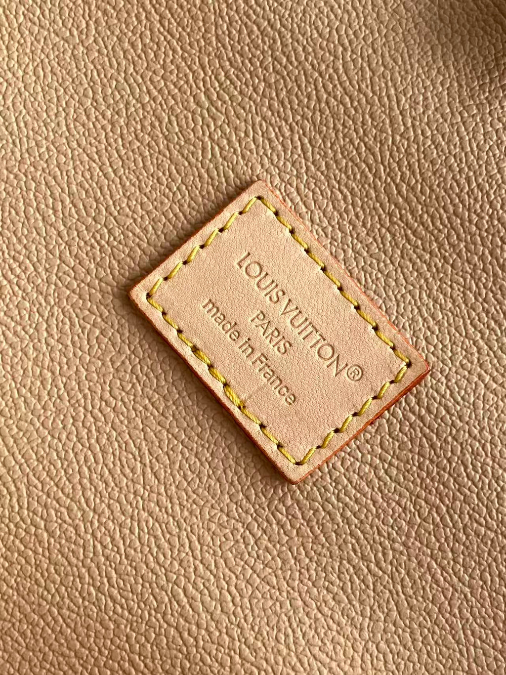 Louis Vuitton leather brand patch reading “Louis Vuitton” and “Made in France”