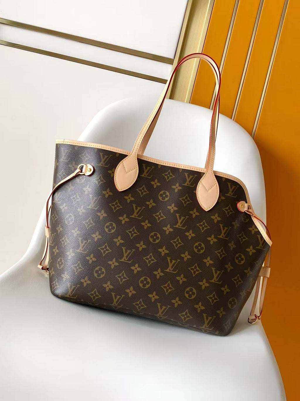 Louis Vuitton monogram tote bag angled front view with tan leather handles and charm