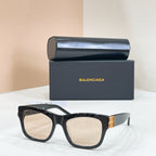 Black square sunglasses with gold logo temple detail and light-tinted lenses