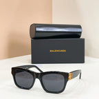 Black square sunglasses with gold logo temple detail and dark-tinted lenses