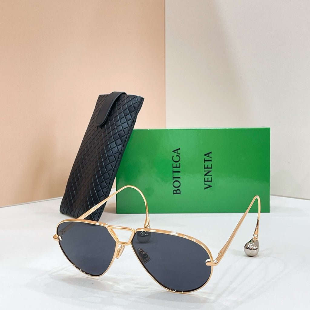 Gold-tone sunglasses with dark blue-tinted lenses on a display stand
