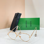Gold-tone sunglasses with light-tinted lenses on a display stand
