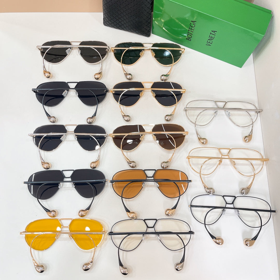 Assorted sunglasses and optical frames with black and gold tones, shown on a display table