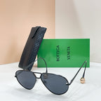 Black aviator sunglasses with dark lenses and gold-tone trim, placed with a black case