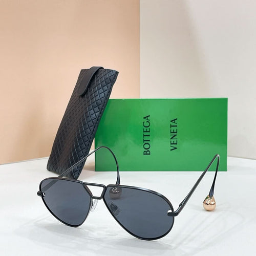 Black aviator sunglasses with dark lenses and gold-tone trim, placed with a black case