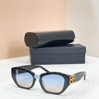 Black cat-eye sunglasses with light blue-tinted lenses and gold-tone B logo temple detail