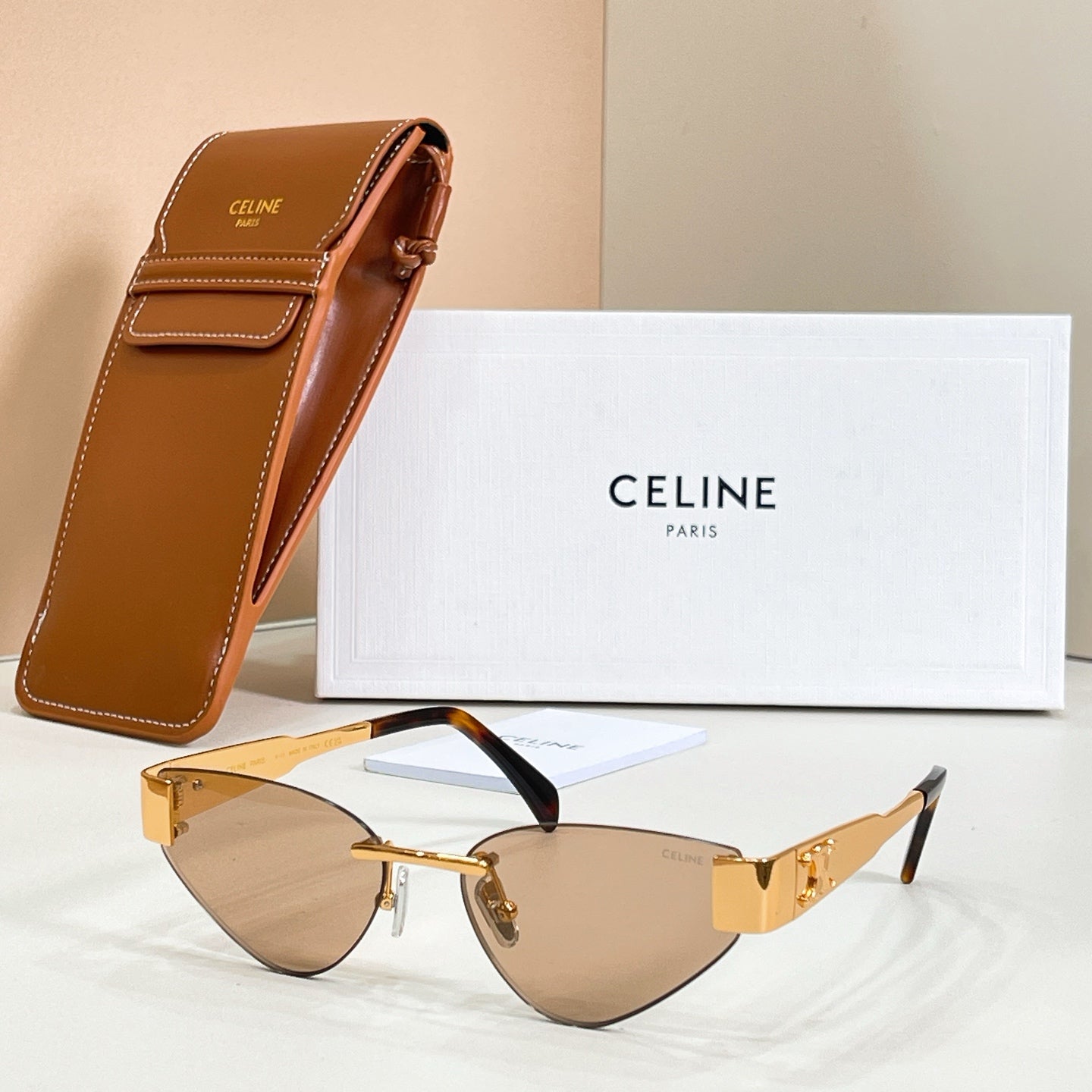 Cat-eye sunglasses with amber lenses and gold-tone frame, black temple detail