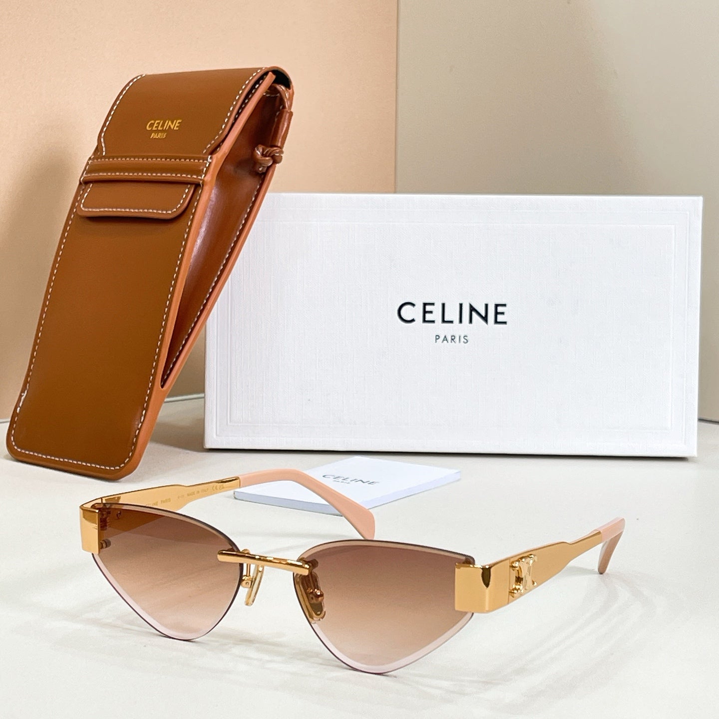 Cat-eye sunglasses with light brown lenses and rose-tinted temples, gold-tone frame
