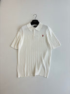 White cable-knit polo shirt with short sleeves, collar, and small red logo
