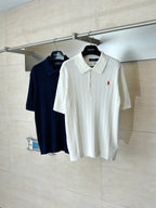 White cable-knit polo shirt with short sleeves and red logo, on hanger