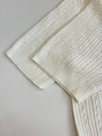 White cable-knit polo shirt sleeve and shoulder detail