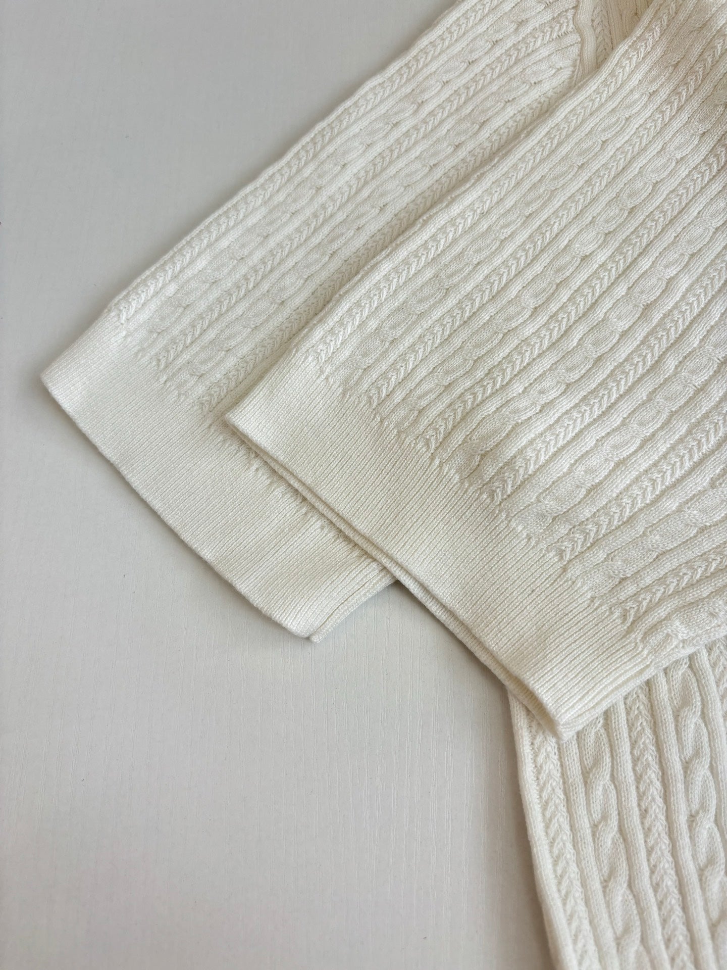 White cable-knit polo shirt sleeve and shoulder detail