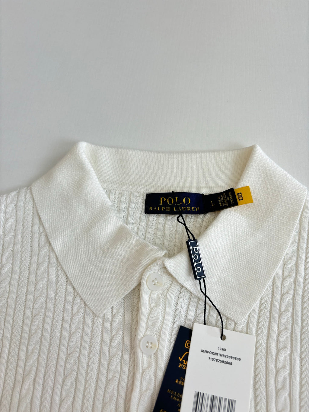 White cable-knit polo shirt collar and placket with Ralph Lauren hang tag