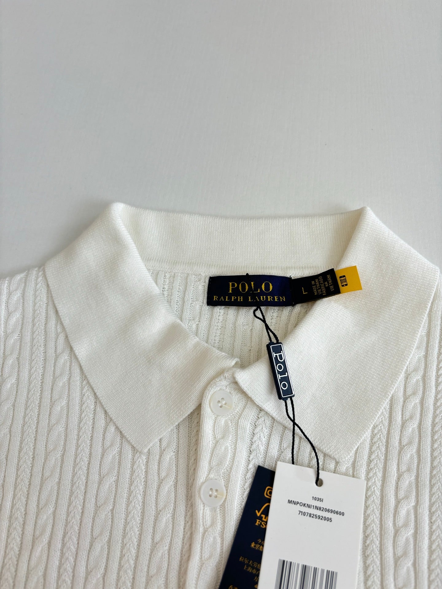 White cable-knit polo shirt collar and placket with Ralph Lauren hang tag