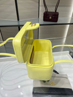 Yellow handbag with top open, showing interior lining and gold logo badge