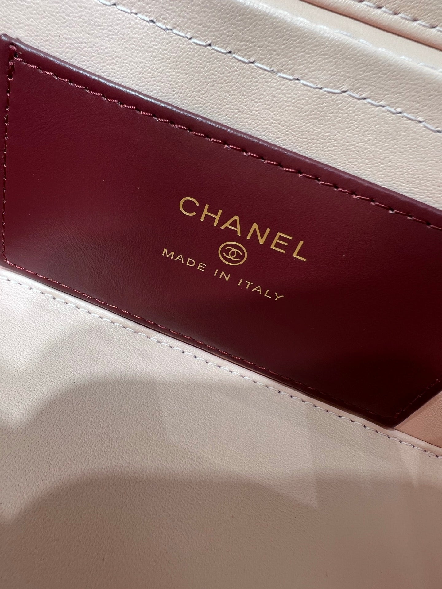 Chanel label on burgundy lining inside bag, reads CHANEL Made in Italy