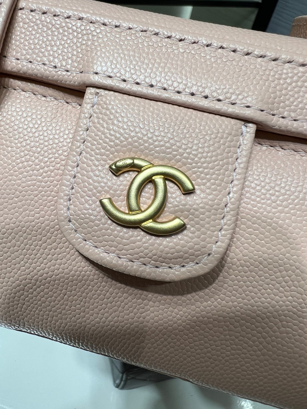 Chanel logo hardware on light pink textured bag flap with stitched edge