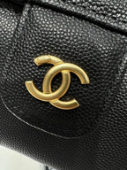 Black Chanel bag close-up of gold CC logo on textured leather flap.