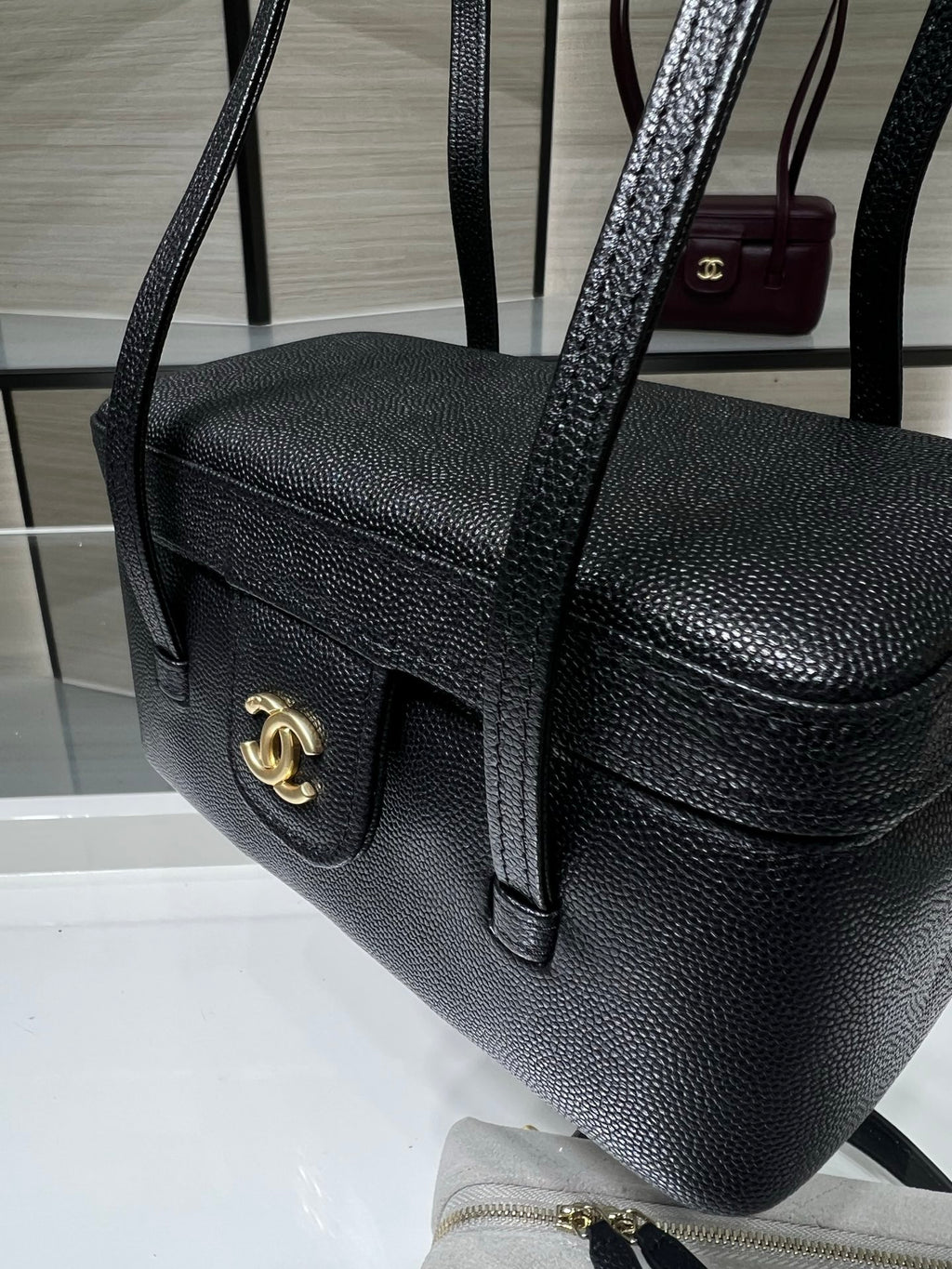Black Chanel handbag with gold CC front tab, textured grain and shoulder strap.