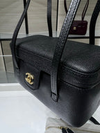 Black Chanel handbag with gold CC front tab, textured grain and shoulder strap.