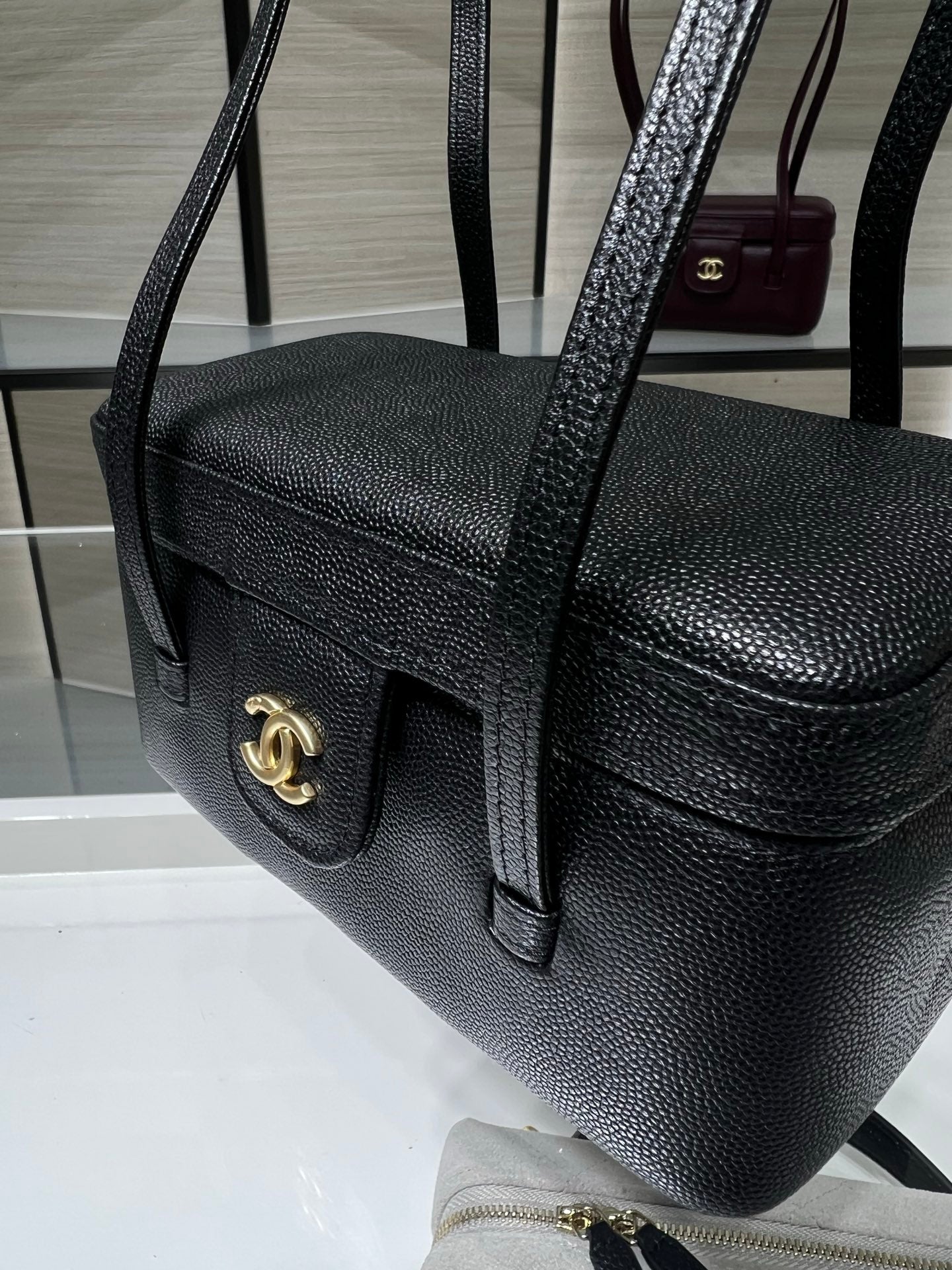 Black Chanel handbag with gold CC front tab, textured grain and shoulder strap.