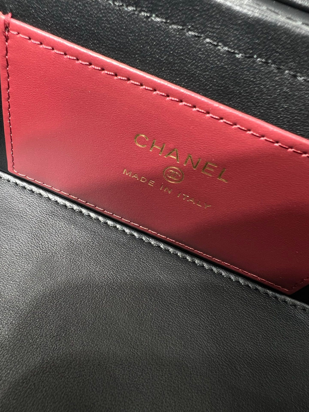 Black Chanel bag interior lining with red panel and CHANEL lettering in gold.
