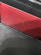 Black Chanel bag interior lining with red panel and CHANEL lettering in gold.