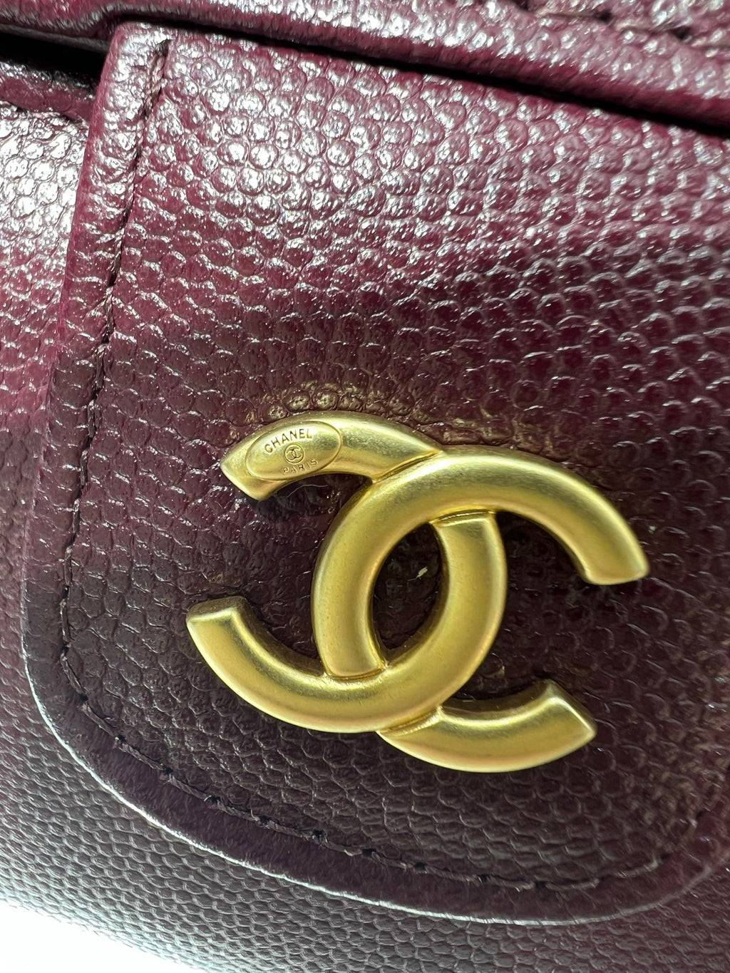 Burgundy Chanel bag close-up with gold CC logo on textured leather flap