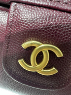 Burgundy Chanel bag close-up with gold CC logo on textured leather flap