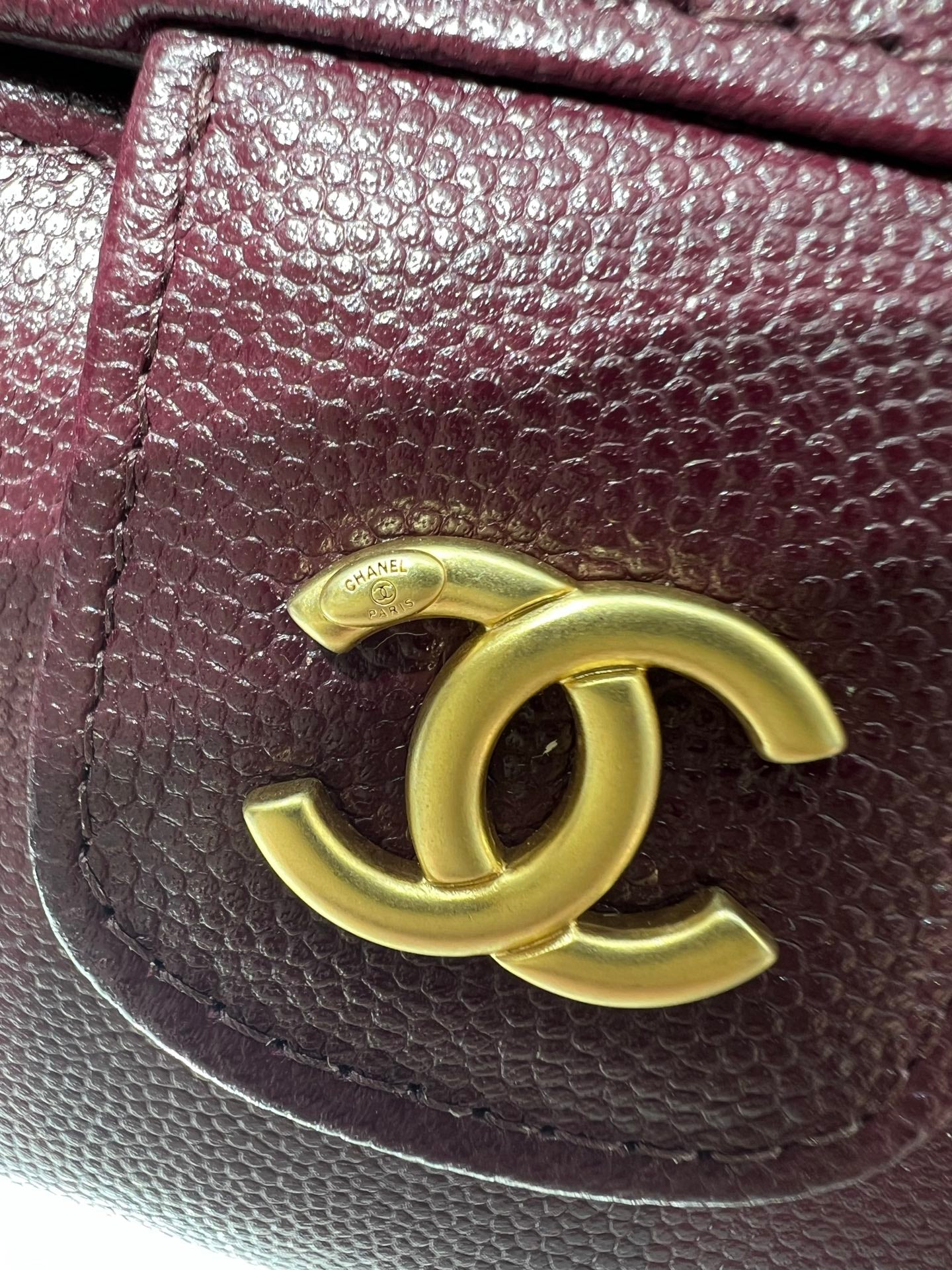 Burgundy Chanel bag close-up with gold CC logo on textured leather flap