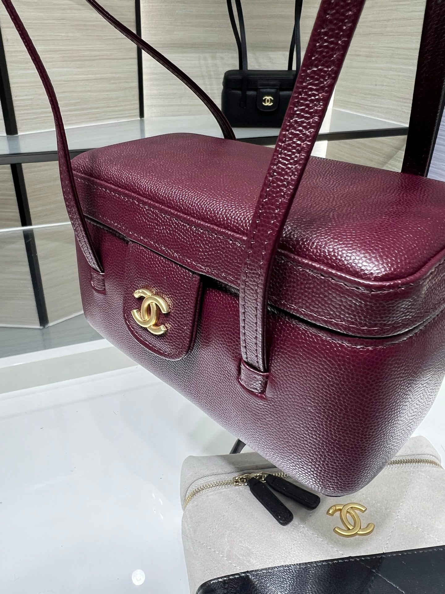 Burgundy Chanel bag front with gold CC emblem and flap clasp, leather top
