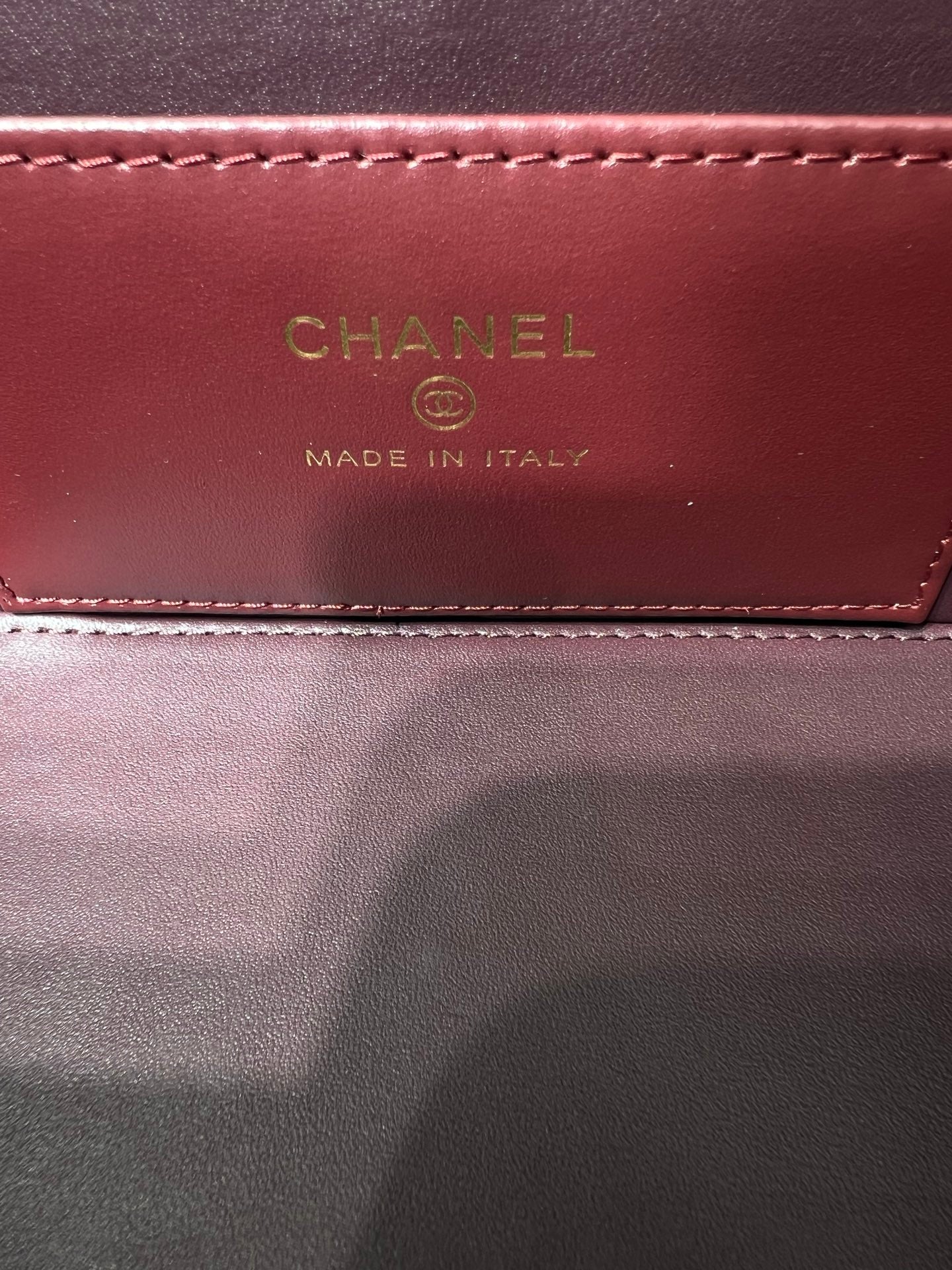 Chanel bag interior label reading CHANEL and MADE IN ITALY on burgundy lining